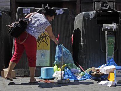 Una mujer deja una bolsa de basura en el suelo en Madrid.