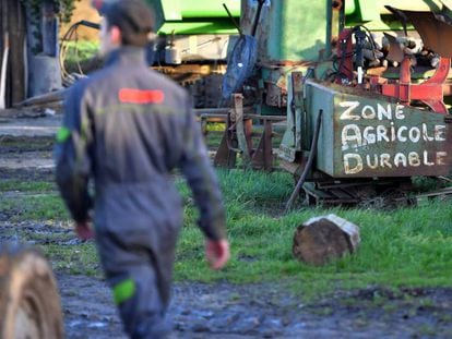 Uno de los residentes de Notre-Dame-des-Landes camina entre maquinaria agr&iacute;cola. Escrito con pintura el letrero &quot;Zona Agr&iacute;cola Durable&quot;.