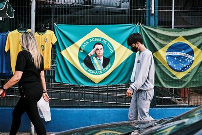 A woman and a child walk next to a Brazilian flag with the face of Bolsonaro, on an avenue in Brasilia, on September 20, 2022.