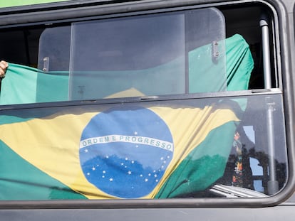 Un partidario de Bolsonaro exhibe una bandera de Brasil en un autobús tras ser desmontado el campamento de bolsonaristas que se había levantado enfrente del cuartel general del Ejército, en Brasilia.