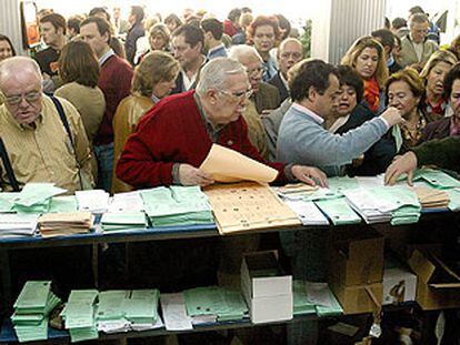 Los electores de un colegio de Sevilla buscan sus papeletas para ejercer su voto.