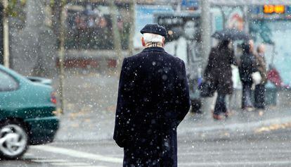 Un hombre camina por una calle de Madrid en medio de la nevada.