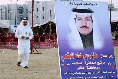 Un saudí camina tras un cartel electoral de un candidato por Provincia Oriental, en Al Jobar.