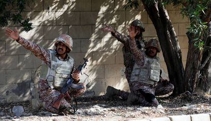 Tres militares paquistaníes se cubren durante el ataque al consulado chino en Karachi (Pakistán).