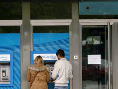 Dos clientes retiran dinero de un cajero de Novagalicia Banco en A Coru&ntilde;a