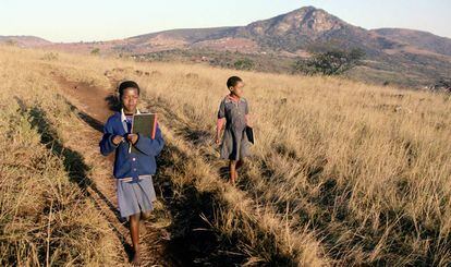 Las huérfanas del sida Pumelele Ndlangamandla (10, derecha) y su hermana Nosipho Ndlangamandla (11) caminan a la escuela en Bhanganoma, en la zona rural de Esuatini. Las cuotas escolares para los huérfanos ahora las paga el Estado, financiado por varios donantes, incluido el Fondo Mundial. Su escuela les enseña tanto materias académicas como habilidades prácticas.