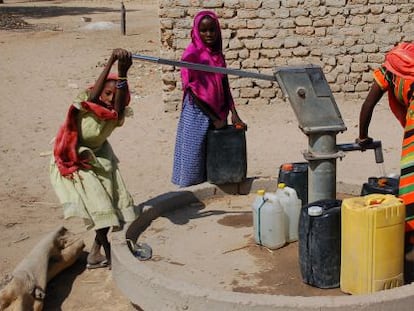 Unas niñas extraen agua con una bomba.