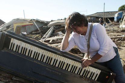 La profesora de música Claudia Vergara llora sobre su piano el martes entre las ruinas de su casa en Constitución.