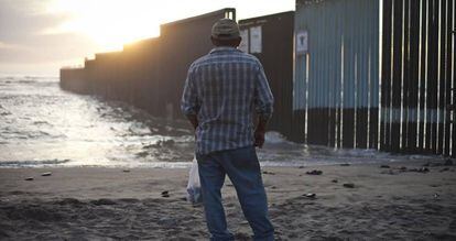Un hombre contempla el muro en la playa de Tijuana