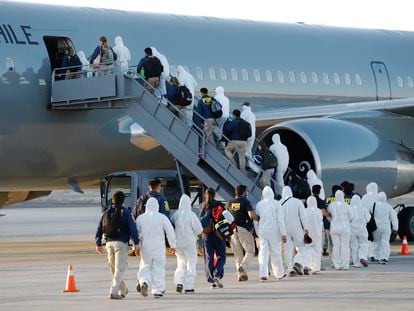 Migrantes venezolanos y colombianos son deportados vestidos con equipo de protección contra la covid-19, en el aeropuerto de Iquique, Chile, este miércoles.