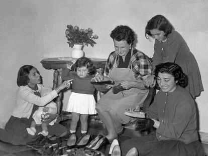 Una madre junto a sus hijas limpiando los zapatos de la familia, en una imagen de archivo de los años 60.