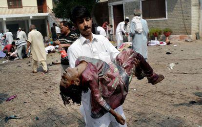 Un joven pakistani lleva en brazos el cuerpo sin vida de una de las víctimas del doble atentado.