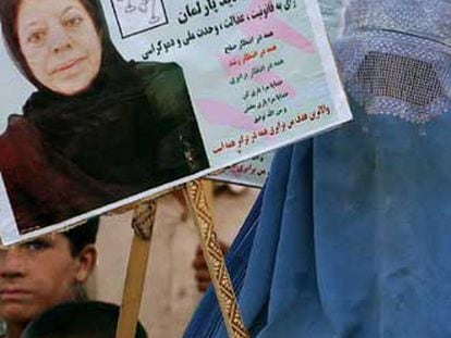 Una mujer con <i>burka</i> porta la foto de la candidata Suraia Perlilka.