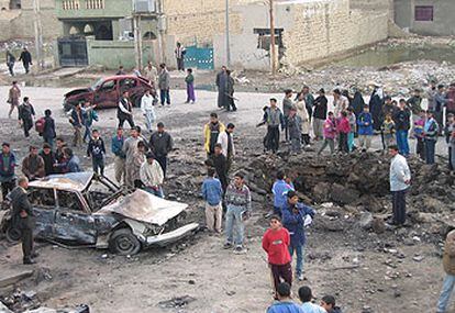 Varios jóvenes de Bagdad se congregan alrededor del cráter creado por la explosión del atentado de ayer.