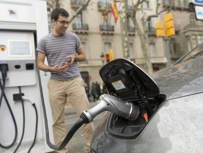 Un home recarrega el seu cotxe elèctric a Barcelona.