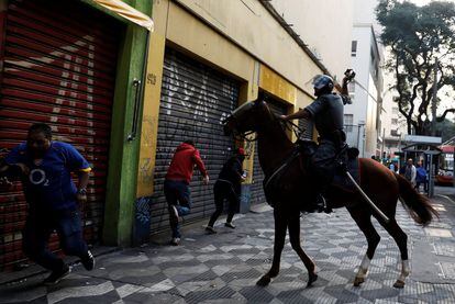 Un policía antidisturbios dispersa a unos integrantes del movimiento sin hogar, en Brasil.