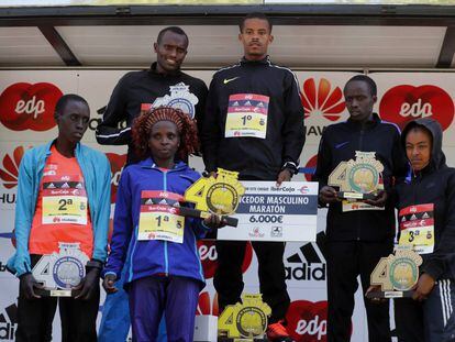 El etíope Bonsa Dida e proclama campeón de la Maratón de Madrid, su compatriota Belete Mekonen, segundo, y del keniano Ronald Kipkoech Korir, tercero, posan en el podio junto con la ganadora en categoría femenina, la keniana Elizabeth Rumokol, Joan Jepchirchir Kigen, segunda, y la etíope Bedatu Hirpa Badane, tercera, tras finalizar la prueba.