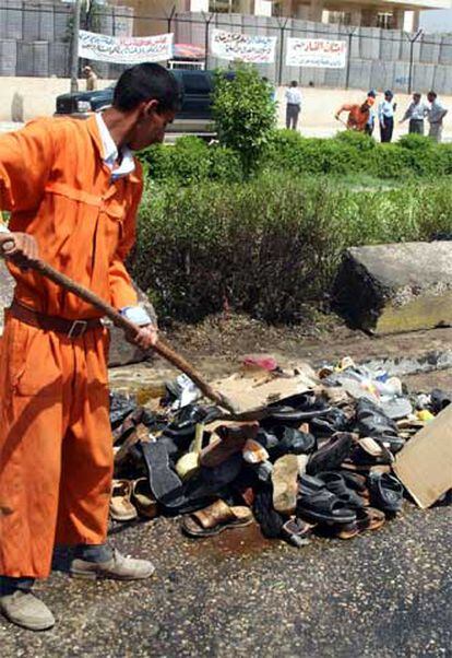 Un operario de la limpieza iraquí retira los zapatos de las víctimas del doble atentado en Hilla.