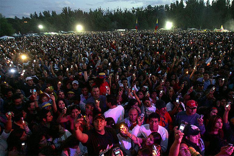 Miles de personas con velas, mecheros y teléfonos móviles rinden homenaje a las víctimas del 11-M durante la fiesta latina celebrada en la Casa de Campo.