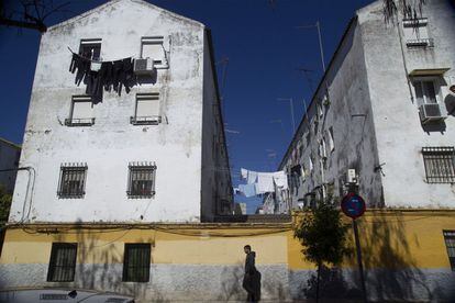 Un hombre camina frente a un edifico del barrio de 'Los Pajaritos' de Sevilla
