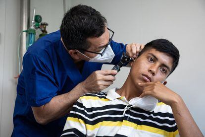 El doctor Ramírez examina el oído de un paciente en su consultorio. Como médico, tiene que repartirse en varias especialidades, con la ayuda de cooperantes. 