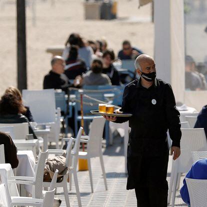 Un camarero atiende las mesas de una terraza de un bar en la playa de la Malvarrosa, en Valencia.