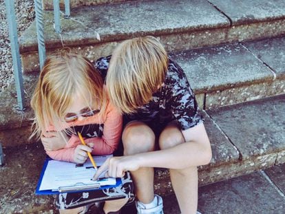 Dos niños estudian juntos en unas escaleras.