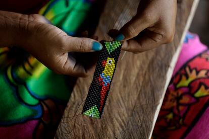 Una artesana de la comunidad de La Marea elabora una pulsera con la imagen de una guacamaya, el 13 de agosto de 2022.