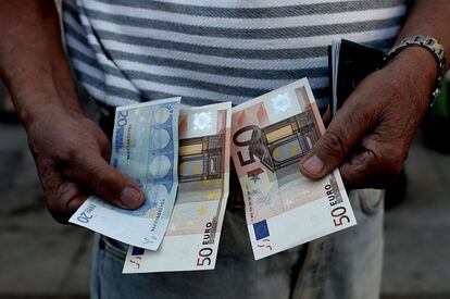 Un pensionista muestra los 120 euros que ha podido sacar del banco. Es la cantidad máxima fijada que podrán sacar para toda la semana en la que de momento estará en vigor el cierre bancario.