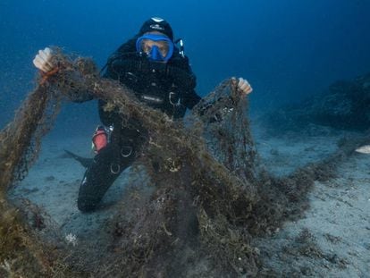 Un buzo que explora los fondos marinos muestra una red de pesca abandonada que acaba de encontrar en Marsella (Francia) en agosto de 2017.