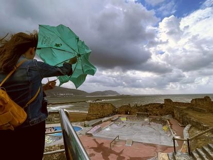 Una mujer trata de abrir su paraguas frente a la playa de Arrigunaga en Getxo (Bizkaia), el pasado 17 de agosto.