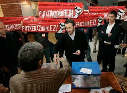 El presidente del PNV, Josu Jon Imaz, en el momento de votar en San Sebastián, hostigado por varios radicales con carteles.