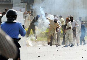 Un manifestante paquistaní lanza gases a la policía en Peshawar.