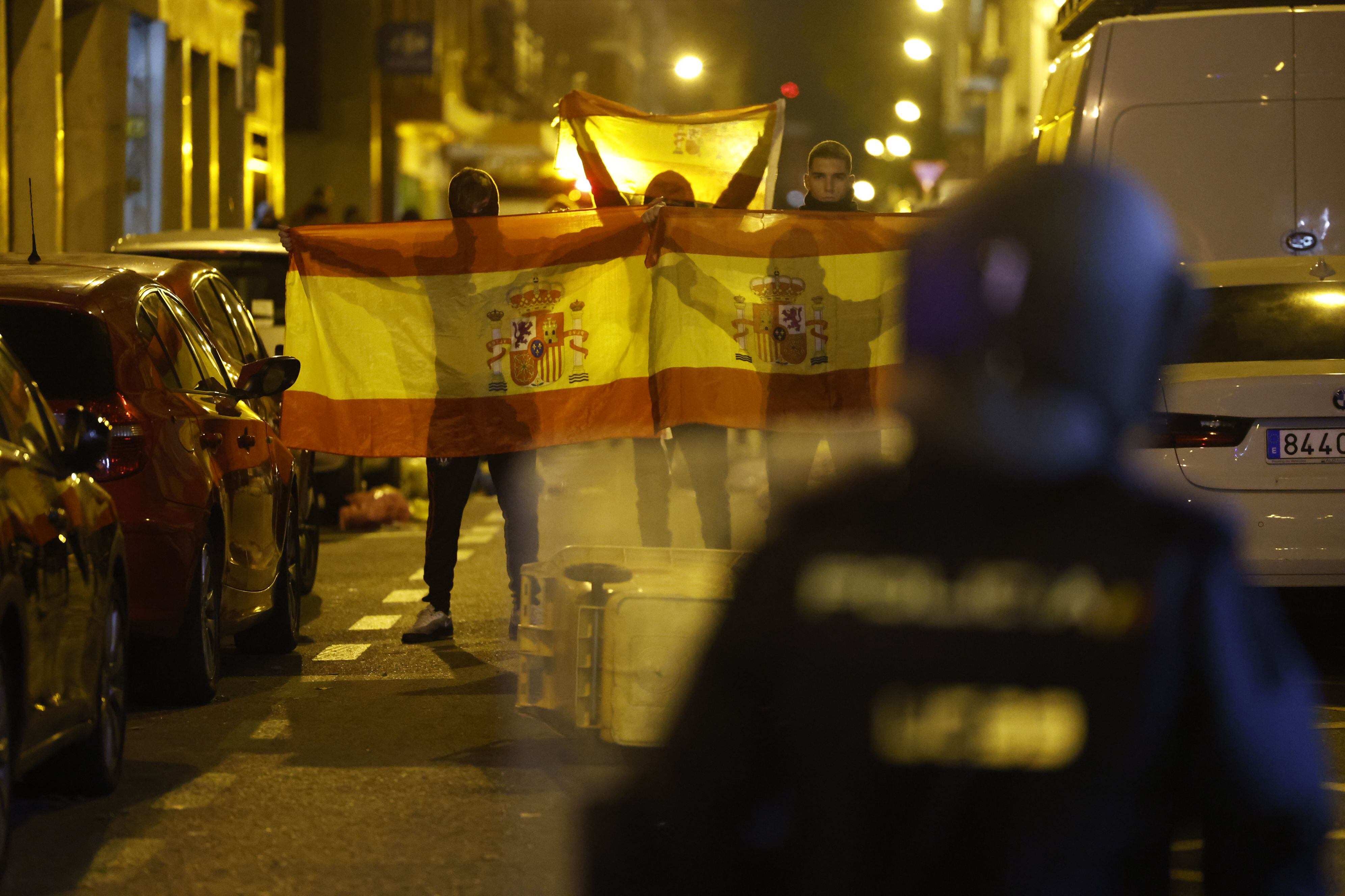 Varios manifestantes sujetan banderas de España durante los enfrentamientos con la Policía, este jueves en Madrid.