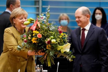 Acting German Chancellor Angela Merkel receives a bouquet from her intended successor, Olaf Scholz, this morning before what is likely to be her last Council of Ministers.