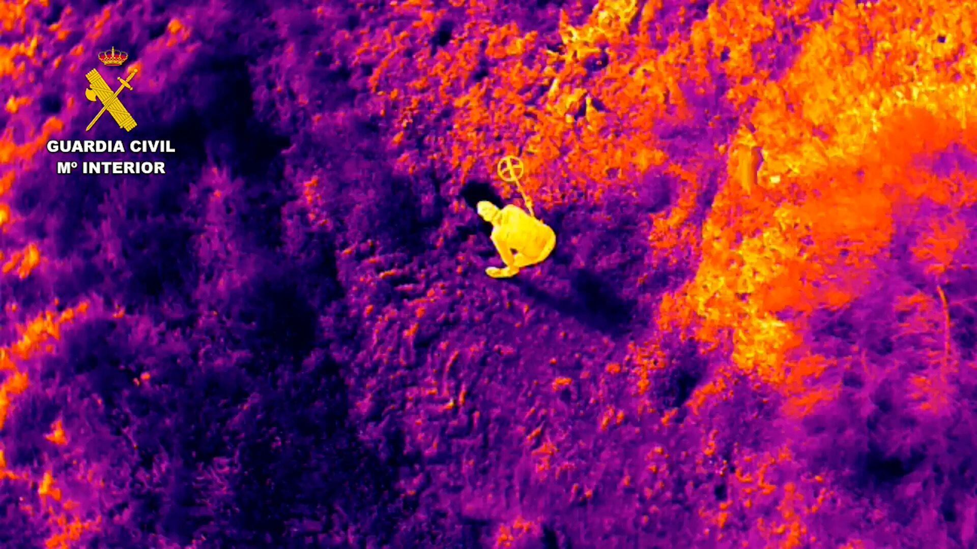 Vista aérea de una cámara térmica que capta a un hombre con un detector de metales.