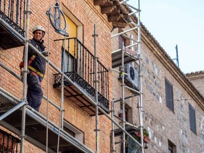 Un obrero de la construcción trabaja sobre un andamio en una calle en Toledo.