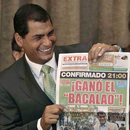 Rafael Correa muestra sonriente un periódico que titula con su victoria.