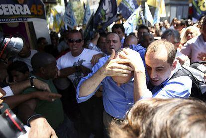 Serra, candidato a las presidenciales brasileñas, se protege la cabeza tras ser alcanzado por un objeto lanzado por partidarios de su contrincante política.