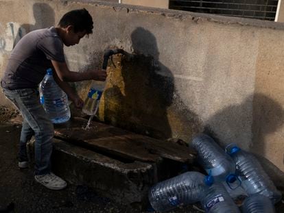 Un niño rellena una garrafa de agua y varias botellas en una fuente pública en el municipio de Byblos, al norte de Beirut.