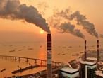 The sun sets near a coal-fired power plant on the Yangtze River in Nantong in eastern China's Jiangsu province on Dec. 12, 2018. Chinese power companies bid for credits to emit carbon dioxide and other climate-changing gases as trading on the first national carbon exchange began Friday, July 16, 2021 in a step meant to help curb worsening pollution. (Chinatopix via AP)