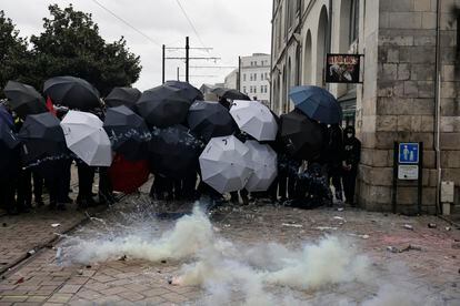 Un grupo de manifestantes se protegen con paraguas de los botes de gases lacrimógenos lanzados por la policía en Nantes, oeste de Francia, este jueves.