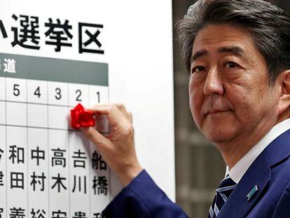 Shinzo Abe, primer ministro de Jap&oacute;n, coloca una rosa sobre el nombre de un candidato que ha obtenido esca&ntilde;o, durante el recuento electoral en Tokio. 