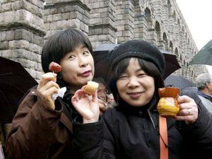 Dos turistas japonesas disfrutan de la gastronomía típica en Segovia.