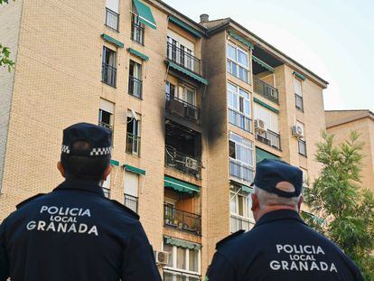 Dos policías frente al inmueble en el que se ha producido el incendio, en la calle Circunvalación del barrio de la chana, en Granada este lunes.