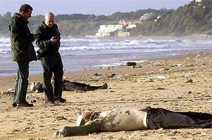 Agentes de la Guardia Civil junto a los cadáveres de dos inmigrantes en la playa de El Buzo, en el Puerto de Santa María.