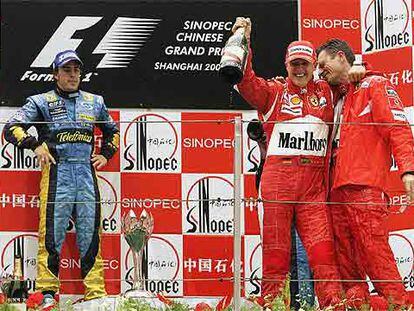 Alonso, en el podio junto a Schumacher, que se abraza a Chris Dyer, ingeniero de Ferrari.