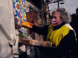 Una voluntaria de Hogar de Cristo entrega alimentos de primera necesidad en un barrio popular argentino.