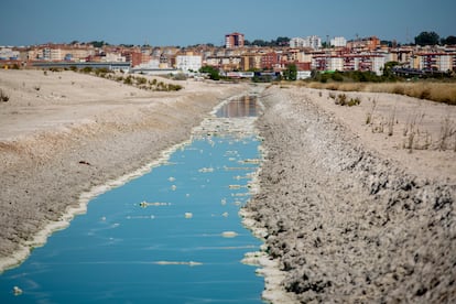 Canal de circunvalación de agua en las balsas de fosfoyesos, con la ciudad de Huelva al fondo.