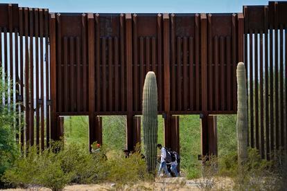 Un grupo de migrantes cruza por un hueco en el muro en medio del desierto entre Sonora y Arizona, en agosto de este año.